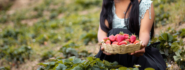 Mujer campesina bastante joven con diadema tejida sosteniendo un tazón lleno de frutas y comiendo...