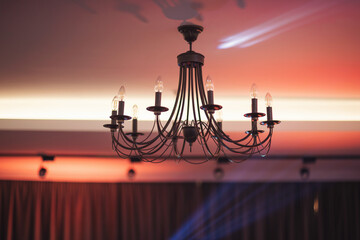 Turning the lights on and off on a beautiful iron candelabra chandelier in restaurant. Traditional,...