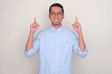 Adult Asian man smiling happy with both hands pointing up