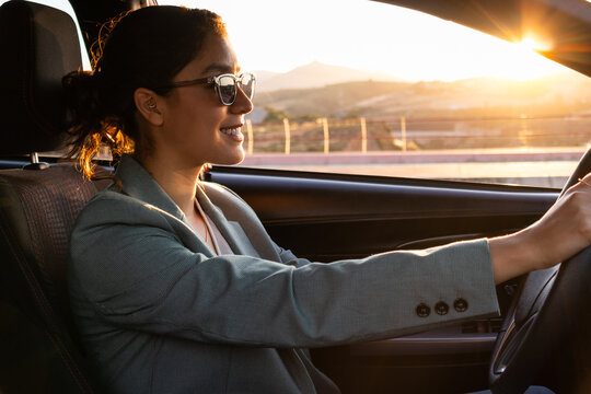 Happy businesswoman in sunglasses driving car