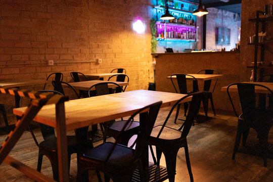 An empty cozy bar interior with wooden tables, metal chairs, and a warm dim lighting ambiance