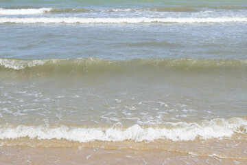Gentle sea waves rolling onto sandy beach, soft surf, natural coastal landscape, tranquil water, summer, relaxation, serene outdoor, vacation, texture, shoreline, editorial stock, travel background.