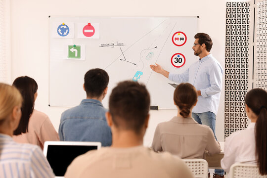 Teacher explaining traffic rules to audience during lesson in driving school