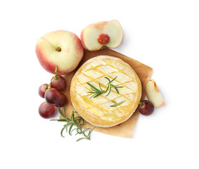 Tasty baked brie cheese with rosemary, grapes and peaches isolated on white, top view