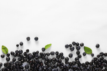 Ripe bilberries and leaves on white background, flat lay. Space for text