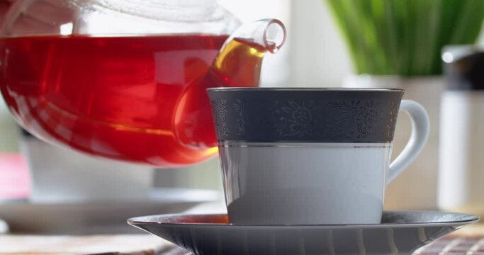 Pouring freshly brewed black loose leaf tea in cup. Lifestyle drinking tea. 