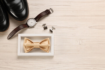 Stylish beige bow tie, shoes, wristwatch and cufflinks on white wooden background, flat lay. Space...