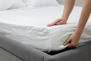 Obraz na płótnie Canvas Woman putting new soft mattress on bed, closeup