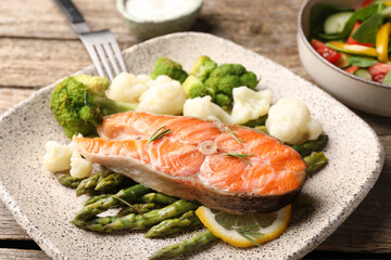 Healthy meal. Tasty grilled salmon with vegetables served on wooden table, closeup