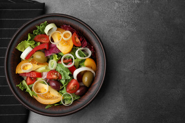 Bowl of tasty salad with leek and olives on brown table, top view. Space for text