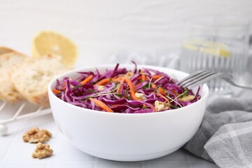 Tasty salad with red cabbage and walnuts on white tiled table, closeup