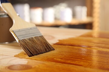 Brush and can with wood stain on wooden surface. Space for text