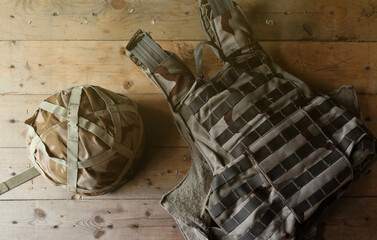 A military helmet of a Ukrainian soldier with a heavy bulletproof vest on wooden table in checkpoint dugout interior
