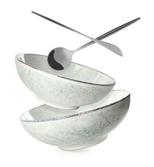 Clean dishes, spoon and knife falling on white background