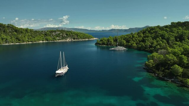 Backwards drone dolley shot of luxury sailing yachts anchored at Mljet Island in Croatia