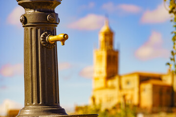 Fototapeta na wymiar Old hydrant and church in town Santa Maria del Campo, Spain.