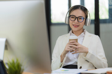 Portrait of happy beautiful Asian woman officer meeting online in video conference, greeting by waving hand, communicating on video call at office desk and smiling female staff worker at workplace.