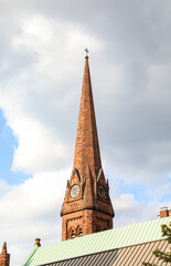 church facade with intricate architecture, towering spire, and vibrant stained glass windows against a clear blue sky