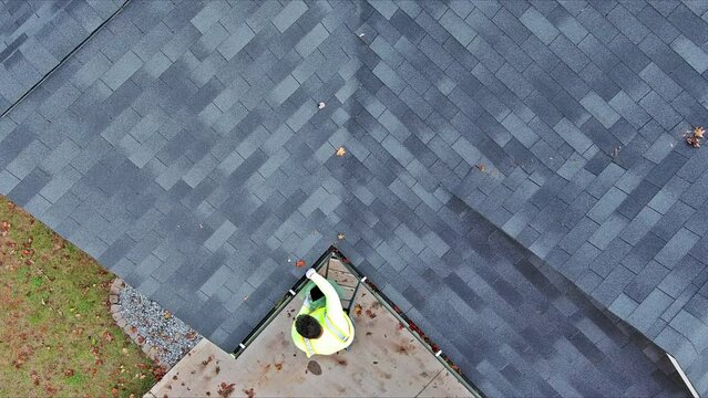 Roof gutter cleaning service worker unclogging debris fallen leaves drain