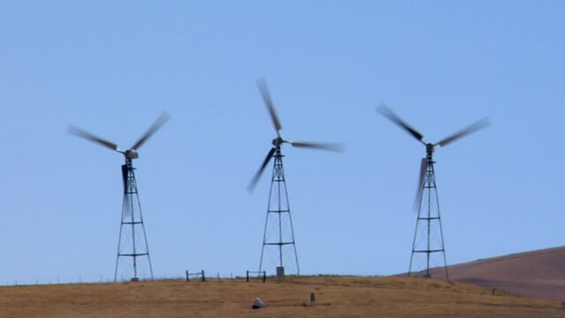 Wind turbines working in Altamont Pass wind farm under blue sky on a sunny day in California, USA