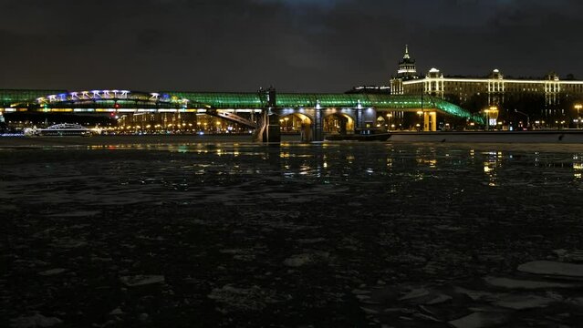 Video of ice drift on the Moscow River on the background of Pushkinsky (Andreevsky) pedestrian bridge at the winter night. Moscow. Russia