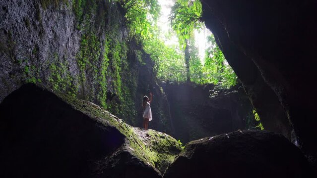 Young woman tourism with rays of light enjoying Tukad Cepung Waterfall at Bali, Indonesia