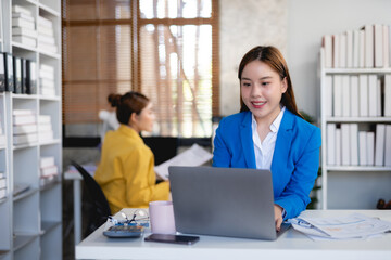 Smiling asian businesswoman using laptop computer at office. Confident Asia businesswoman sitting happily in the office.