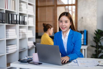 Smiling asian businesswoman using laptop computer at office. Confident Asia businesswoman sitting happily in the office.