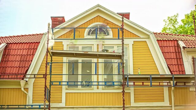 Time-lapse of men on scaffolding painting house orange hyper lapse