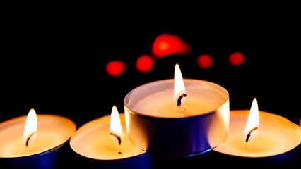 Three burning candles on black background
