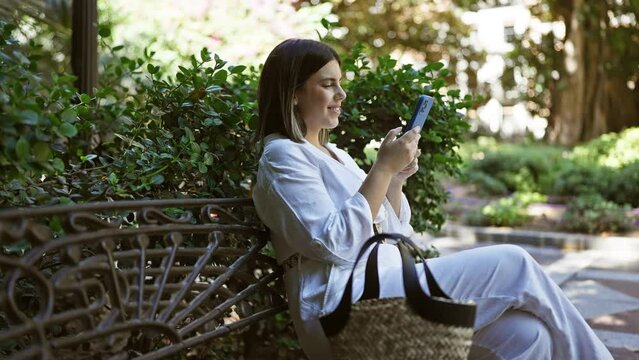 Young beautiful hispanic woman smiling sitting on a bench using smartphone at park