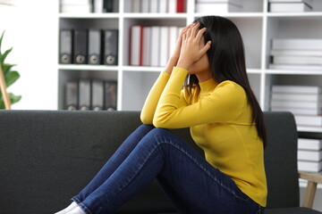 Young Asian woman with sickness and fever sitting on sofa at home. Young woman with depressed,...