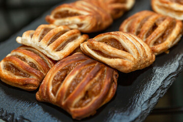 Appetizing crispy pastries with jam on a black stone tray. Organizing events and business meetings. Close-up.