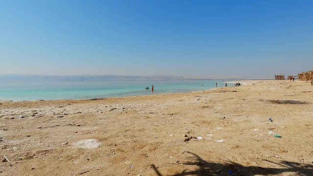 Wide angle view from tropical cabana of people playing and walking in the dead sea