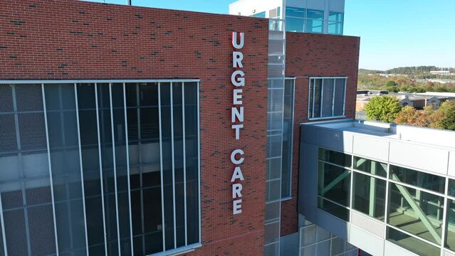 Urgent Care sign on modern brick medical center. Aerial establishing shot.