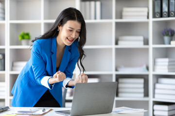 Woman using laptop looks excited, happy to succeed and receive a bonus.