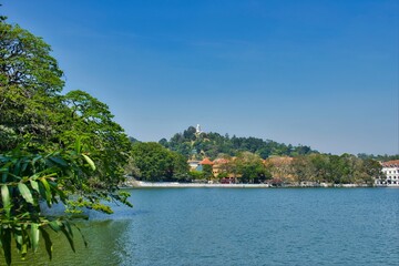 KANDY, SRI LANKA - FEBRUARY 10, 2021: View on Kandy lake and big Buddha on top of the hill. Kandy is home of The Temple of the Tooth Relic, one of the most sacred Buddhist places of worship. 