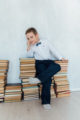 Little boy sitting on stacks of educational books in library