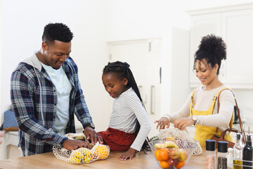 Happy african american family unpacking groceries on table in kitchen at home, copy space