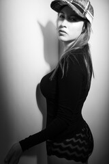 Fototapeta premium Black and white portrait of a caucasian woman wearing a plaid baseball cap and a black shirt. She has blonde hair and is looking at the camera. 