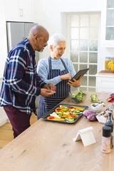 Foto auf Acrylglas Diverse senior couple preparing meal using tablet in kitchen © WavebreakMediaMicro