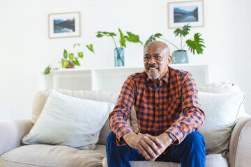 African american senior man sitting on sofa in sunny living room