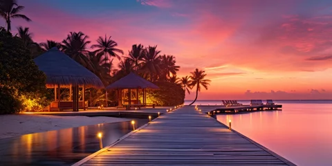 Foto op Plexiglas Sunset on Maldives island, luxury water villas resort and wooden pier. Beautiful sky and clouds and beach background for summer vacation holiday and travel concept © Rozeena