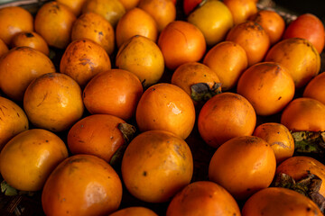 Ripe orange persimmons. on the table in the market. A bunch of organic persimmon fruits at a local farmers market in Dalat city, Vietnam. Persimmon background. Flat lay.