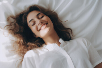 A joyful young woman lies in bed. The concept of relaxation and happiness at home.