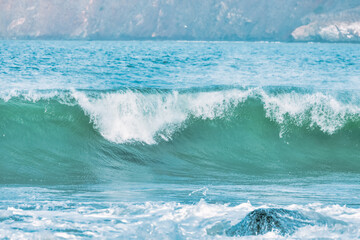 Wave splashes close-up. Crystal clear sea water hitting rock formations in the ocean in San Francisco Bay, blue water, pastel colors.