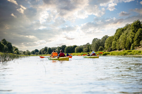 Group of friends kayaking enjoy bpat trip down a scenic river with a dramatic cloudy sky above