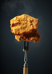 Hot fried schnitzel on a fork.