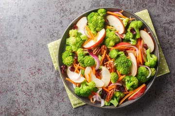  Homemade fresh diet salad of broccoli, apple, pecans, red onion, carrots and cranberries close-up in a plate on the table. Horizontal top view from above © FomaA