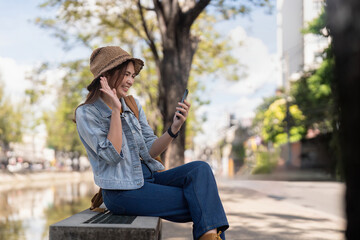 Asian woman in city street using mobile phone while taking selfie